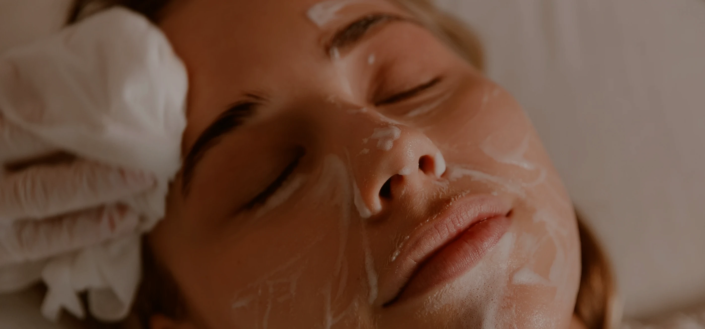 A close-up of a woman receiving an ultrasound neck examination by a gloved medical professional.