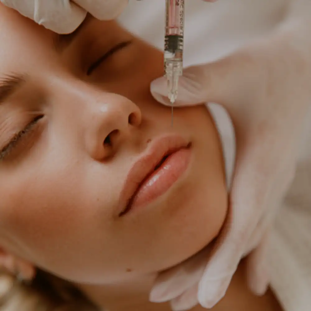 Close-up of a woman's face receiving a cosmetic injection in her cheek from a gloved hand.